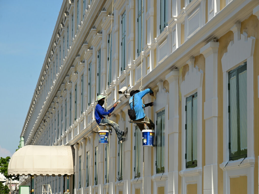 Workers suspended on ropes painting the facade of a tall building