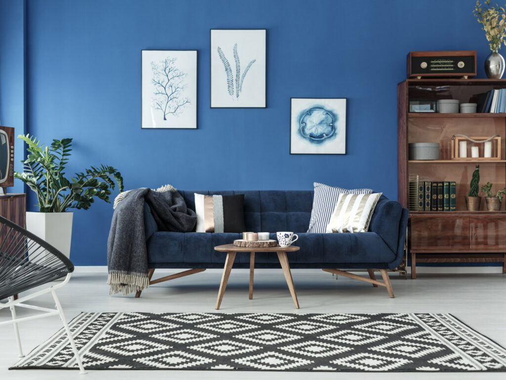 Stylish living room with blue sofa and modern decor against a blue wall.