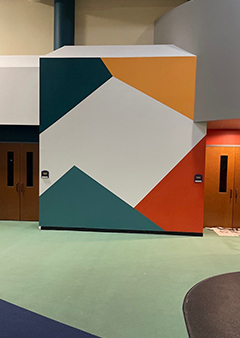 Colorful geometric wall mural with abstract shapes in a hallway.