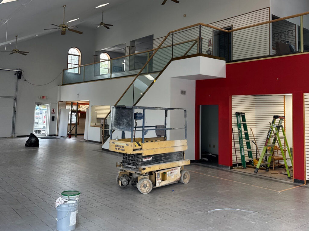 Spacious, clean warehouse interior with ladders and a lift machine.