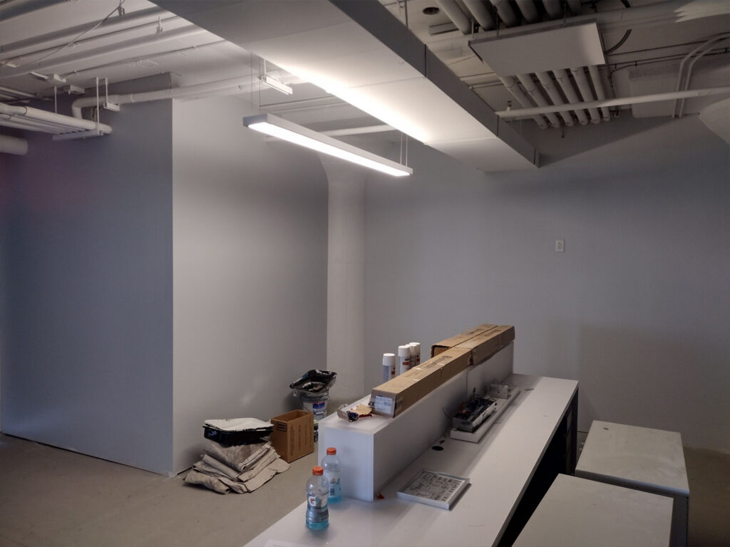 Interior view of an unfinished office space with visible pipes and boxes.