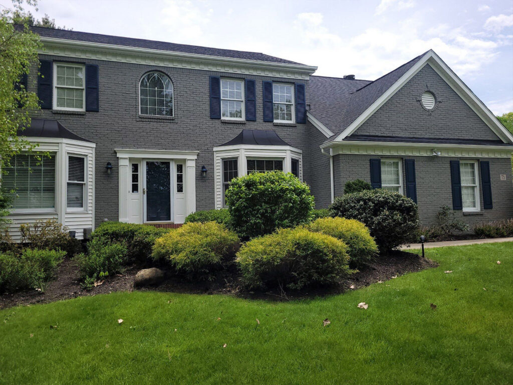 Charming two-story gray brick house with lush front yard