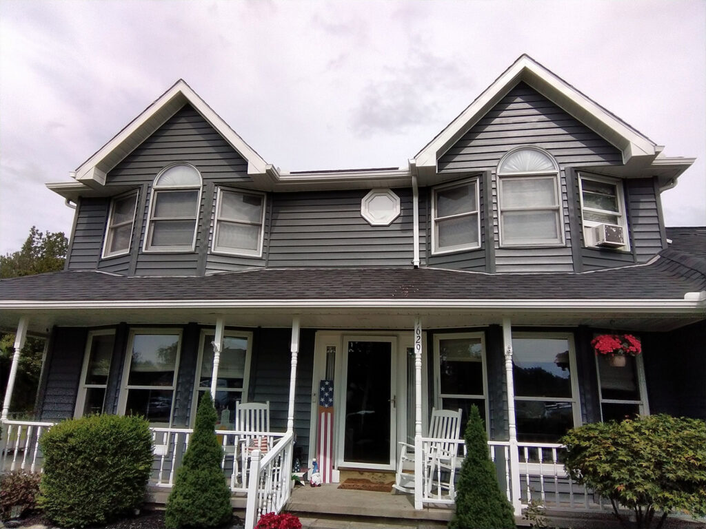 Charming grey house with gable roofs and front porch.
