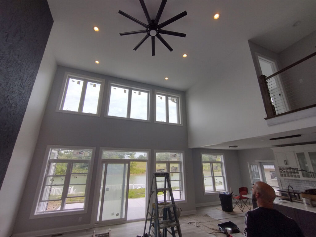 Spacious modern living room with large windows and ceiling fan