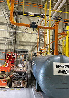 Industrial facility with large anhydrous ammonia tank and piping system.