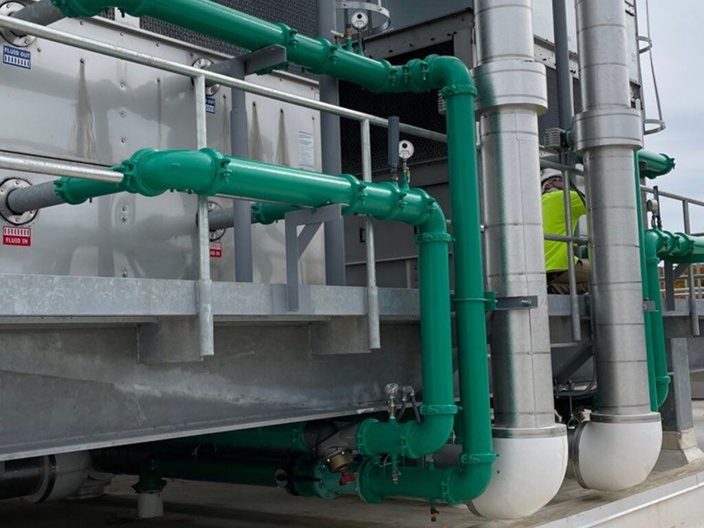 Industrial pipes and ducts on a rooftop with maintenance worker.