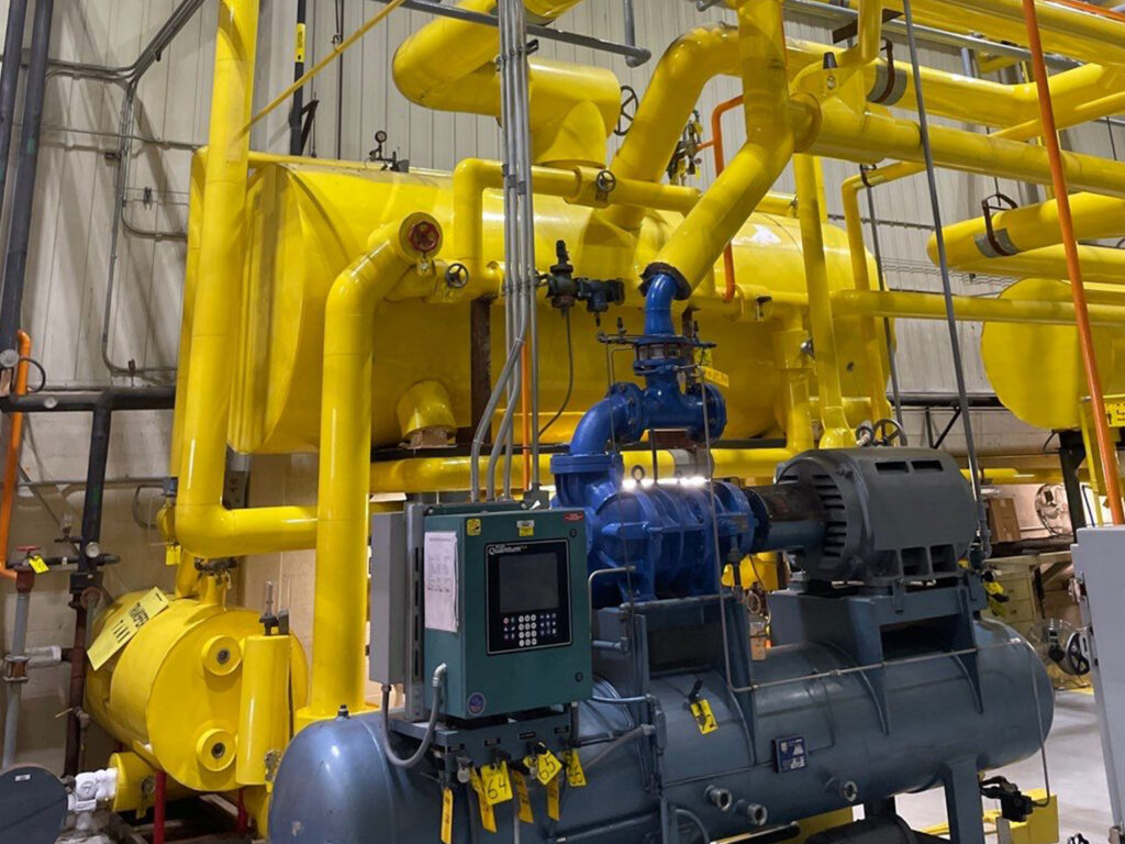 Industrial machinery with yellow pipes in a factory setting.