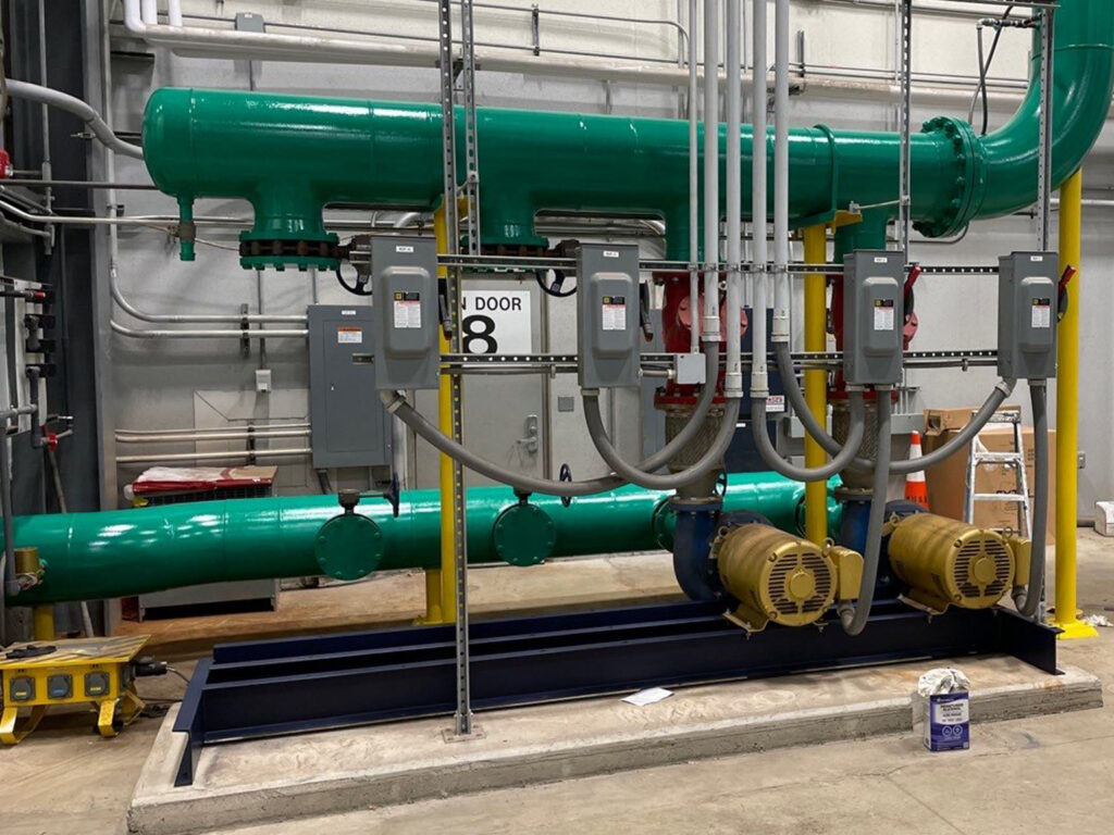 Industrial green piping system with connected machinery in a facility.