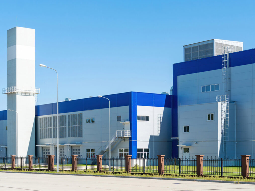Modern industrial building with blue and white exterior under clear sky.