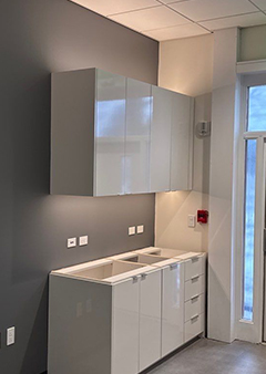 Modern kitchen with sleek white cabinets and gray walls, emphasizing simplicity.