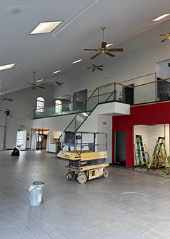 Interior of a spacious room under renovation with scaffolding and ladders.