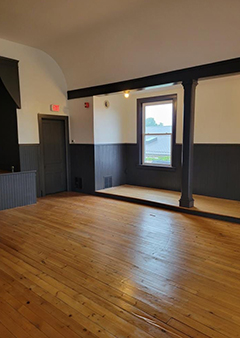Spacious empty room with wooden floors and a large window.
