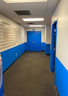 Bright blue and white corridor with double doors at the end
