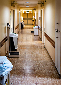 Empty hospital corridor with medical equipment and open doors.