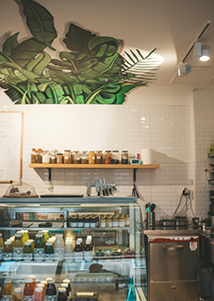 Small cafe interior with shelves of jars and a juice refrigerator