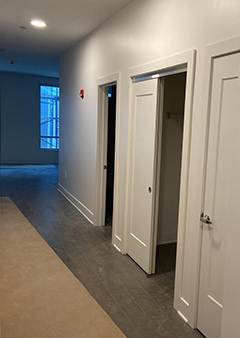 Modern apartment hallway with three white doors and natural lighting.