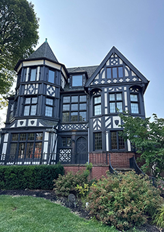 Elegant Tudor-style house with black and white facade and a lush garden.