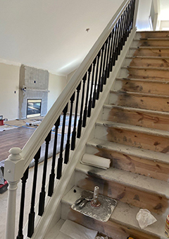 Partially renovated staircase with wooden steps and freshly painted railing.