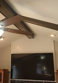 Modern living room with large TV and stylish ceiling beams