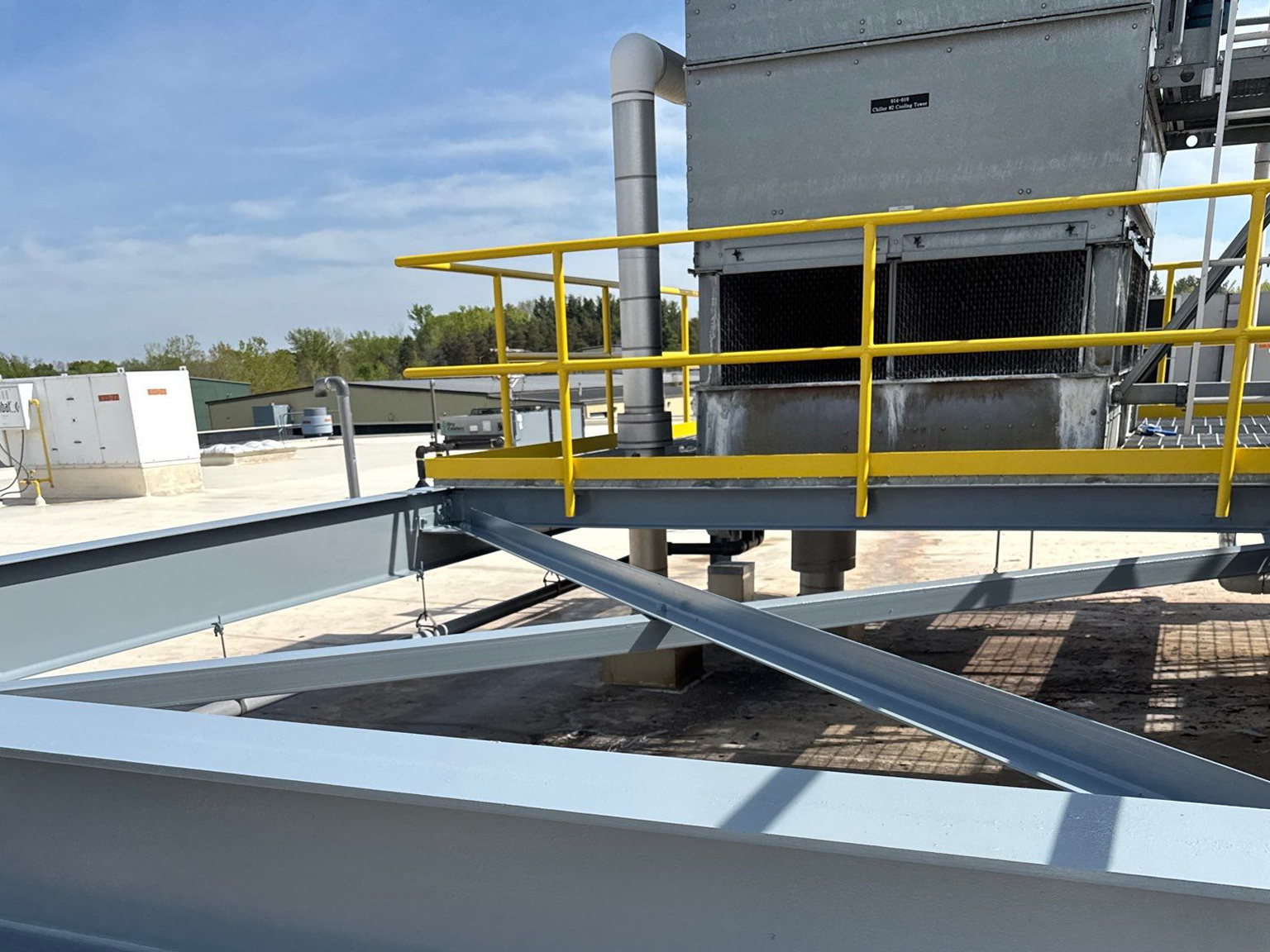 Industrial cooling tower with yellow safety railings on a rooftop.