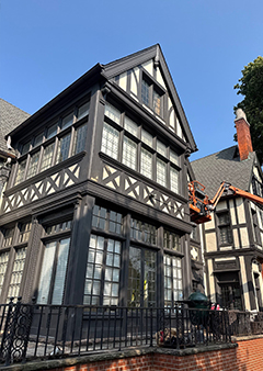Tudor-style house with intricate woodwork and large windows under a clear sky.