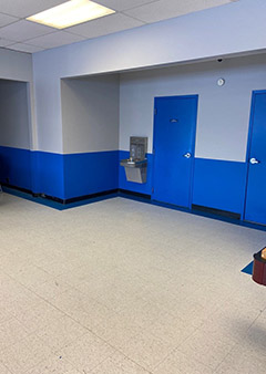 Empty waiting room with blue doors and a water fountain.